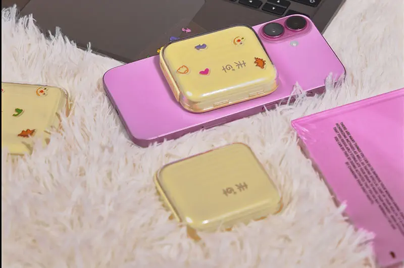 Yellow AJ04 magnetic wireless power bank attached to a pink phone