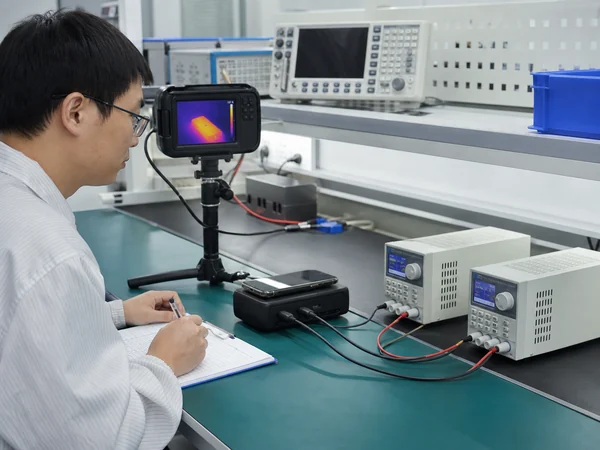 Chinese engineer testing shared output and temperature on a multi-port wireless power bank