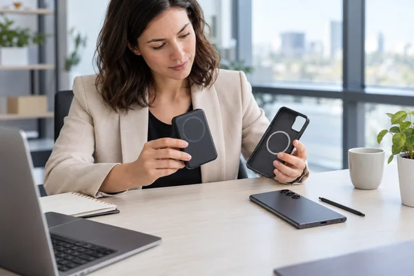 Procurement buyer comparing an unbranded magnetic power bank and phone case beside a smartphone and stylus.