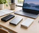 Three unbranded power banks arranged beside a laptop on a procurement desk.