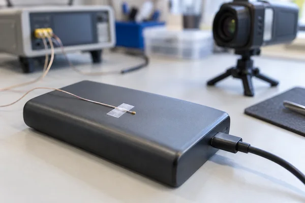 Thermocouple secured to the surface of a power bank with an infrared camera in the background
