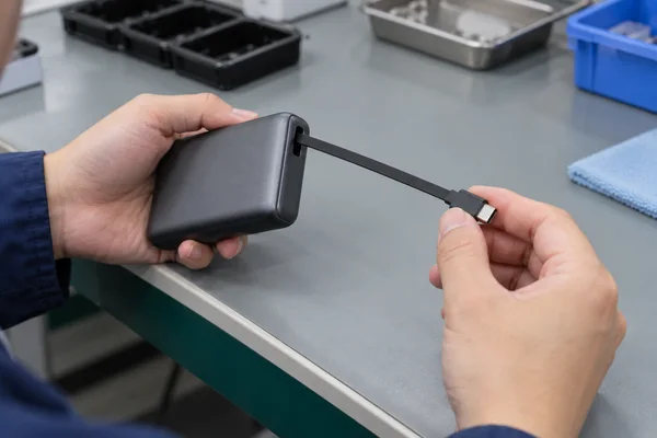 Technician checking the extension and USB-C plug of a retractable power bank cable